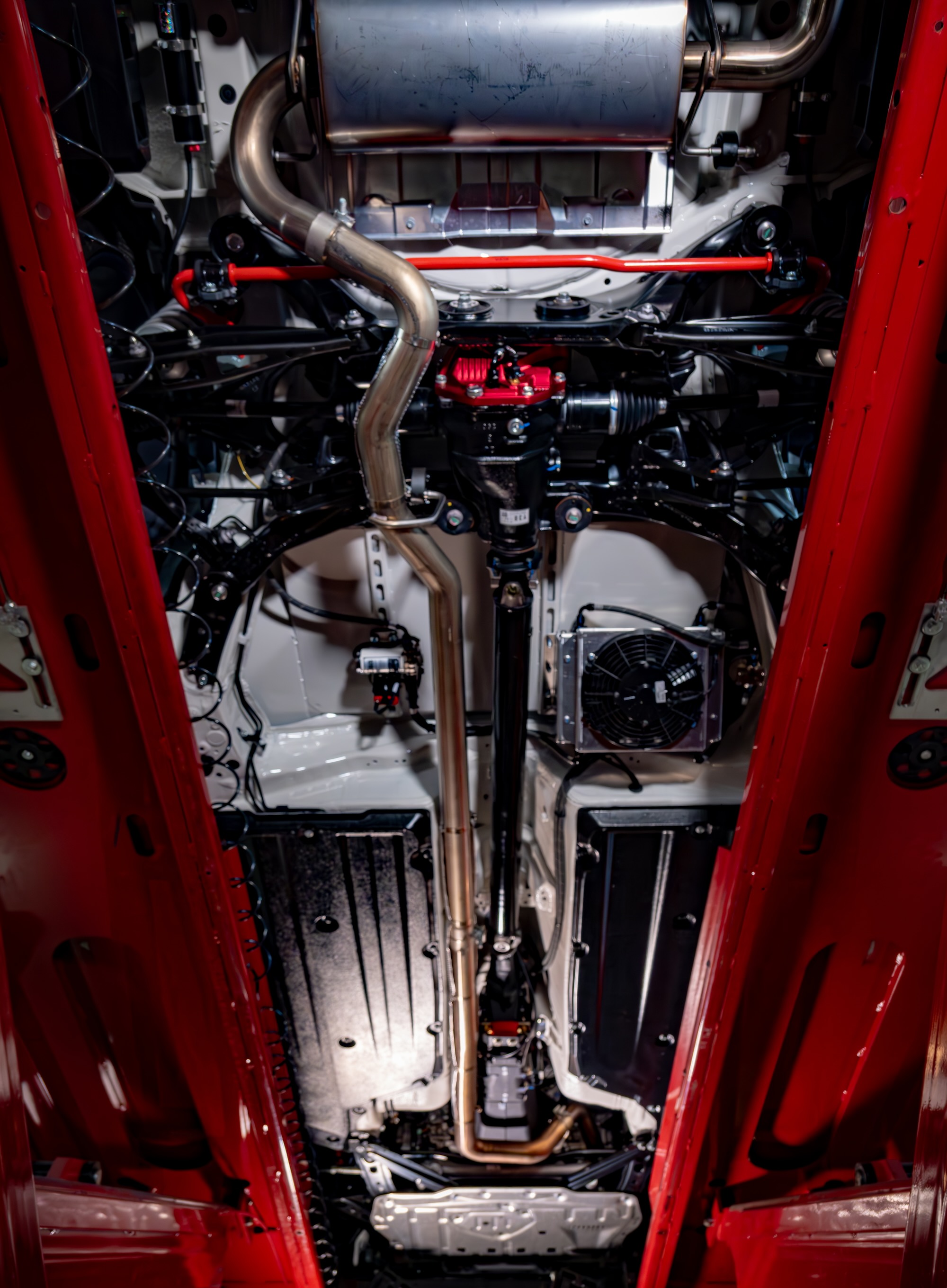 You can see the fan in the middle right of this photo and the diff pump to the left of the exhaust. This fan draws air across both the transmission and differential cooler cores (not visible in this photo). Photo from Bring A Trailer.